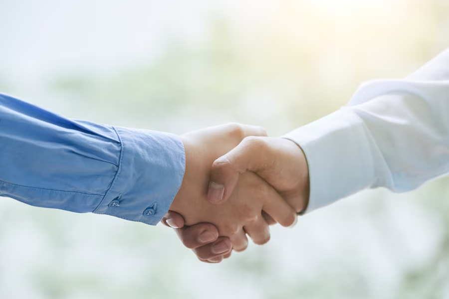 Two hands wearing long sleeves performing a handshake