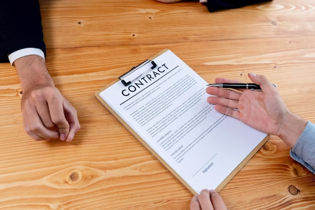 Two people facing each other at a table, one holding a contract and a pen